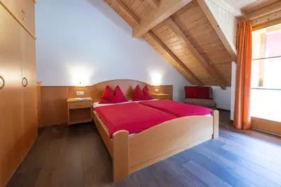 a bedroom with a large bed with red pillows at Ferienwohnungen Fuchsleitenhof am See in Caldaro