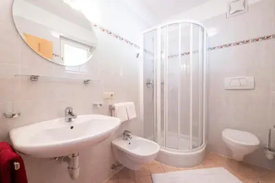 a white bathroom with a sink and a shower at Ferienwohnungen Fuchsleitenhof am See in Caldaro