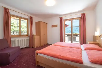 a bedroom with a bed and a couch and windows at Ferienwohnungen Fuchsleitenhof am See in Caldaro