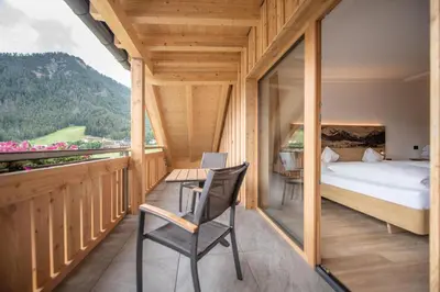a bedroom with a bed and a table and a chair at Hotel Condor in San Vigilio Di Marebbe