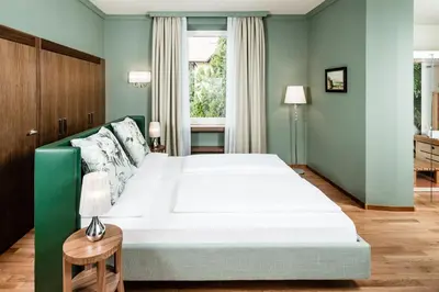 a bedroom with a large white bed and a window at Villa Bavaria in Merano
