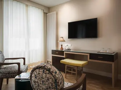a hotel room with a desk with a television on the wall at Villa Bavaria in Merano