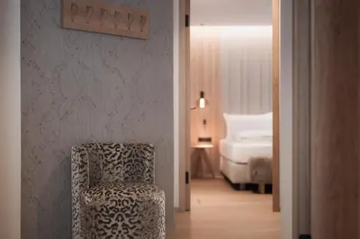 a room with a chair and a bedroom with a bed at Mountain Residence CLARA in Riscone