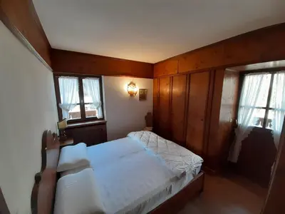 a bedroom with a bed and two windows at Casa elegante in San Vito di Cadore