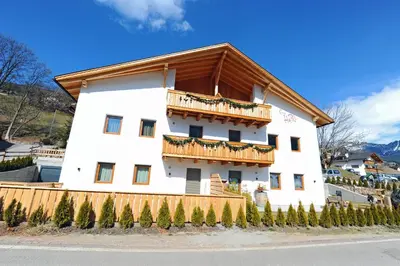 a large white building with a wooden balcony at Mountain Apartment Hapeli in Ortisei