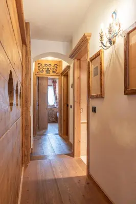 a hallway in a home with wooden floors and a chandelier at Casa Col, vicina alle piste da sci e con vista Dolomiti in Cortina dʼAmpezzo