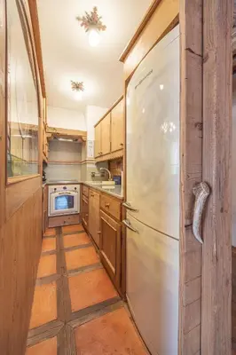 a kitchen with a refrigerator and wooden cabinets at Casa Col, vicina alle piste da sci e con vista Dolomiti in Cortina dʼAmpezzo