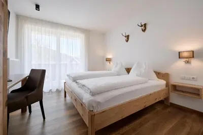 a bedroom with a bed and a desk and a window at Mira Sabiona Guesthouse in Gufidaun