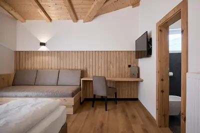 a bedroom with a bed and a desk with a chair at Mira Sabiona Guesthouse in Gufidaun
