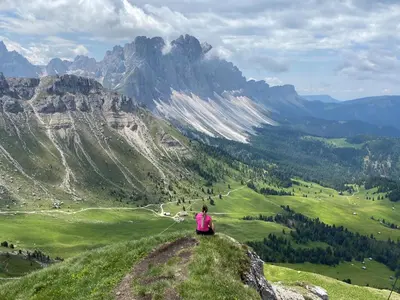 a woman sitting on a hill looking at a mountain at Mira Sabiona Guesthouse in Gufidaun