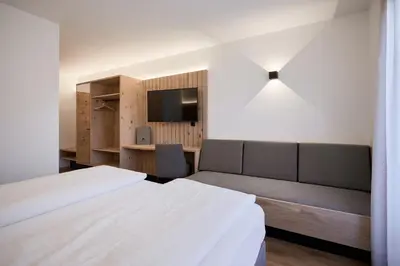 a bedroom with a bed and a couch and a tv at Mira Sabiona Guesthouse in Gufidaun