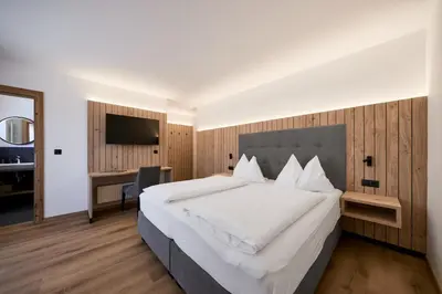 a bedroom with a large white bed and a desk at Mira Sabiona Guesthouse in Gufidaun