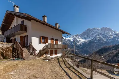 a house on a hill with mountains in the background at Casa Caracoi in Rocca Pietore