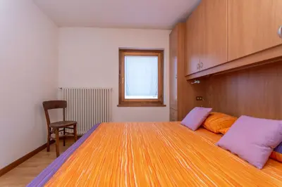 a bedroom with a large bed with purple and orange pillows at Casa Caracoi in Rocca Pietore