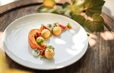 a white plate with food on a wooden table at Taubers Unterwirt Aktiv & Vitalhotel in Feldthurns