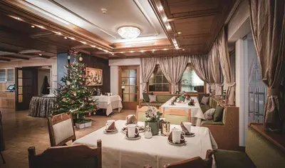 a dining room with a christmas tree and tables at Taubers Unterwirt Aktiv & Vitalhotel in Feldthurns