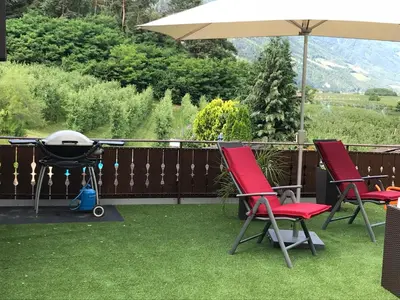 a grill and two chairs and an umbrella on a lawn at Saringerhof in Rablà