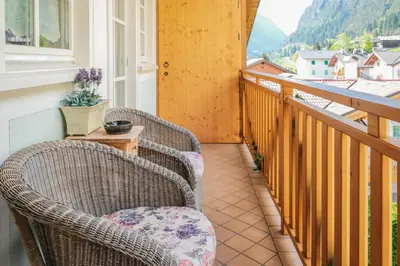 a balcony with two wicker chairs and a table at La Casa Verde in Canale San Bovo