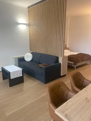 a living room with a blue couch and a bed at Appartament Tribulaun in Colle Isarco
