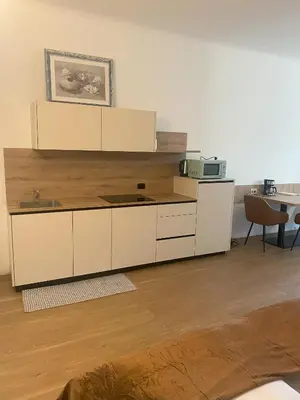 a large kitchen with white cabinets and a table at Appartament Tribulaun in Colle Isarco