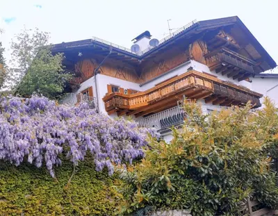 a building with purple flowers in front of it at Haus Gläserer apartments in Villandro