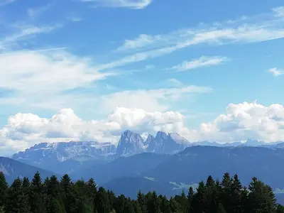 a view of a mountain range with clouds and trees at Haus Gläserer apartments in Villandro