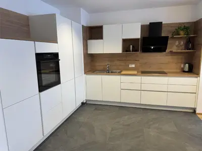 a kitchen with white cabinets and a sink at Haus Gläserer apartments in Villandro