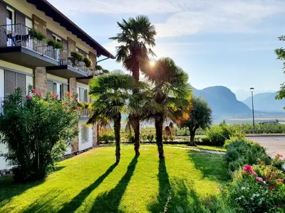 a yard with palm trees in front of a building at Zeder Kraiterhof in Andrian