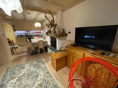 a living room with a flat screen tv and a kitchen at Love Mountain House in Campestrin
