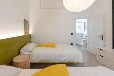 two beds in a room with white walls and yellow sheets at La Finestra sul Peller, Coredo Ospitar in Coredo