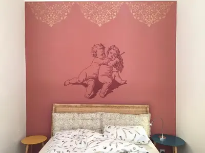a bedroom with a wall with a painting of two children hugging at Schöne Altstadtwohnung im Herzen der Stadt in Bolzano
