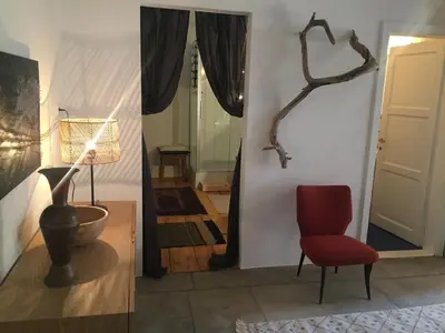 two pictures of a room with a red chair and a door at Schöne Altstadtwohnung im Herzen der Stadt in Bolzano