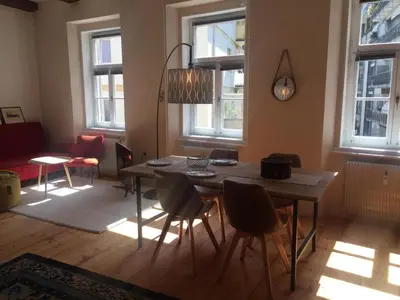 a dining room with a table and chairs and windows at Schöne Altstadtwohnung im Herzen der Stadt in Bolzano
