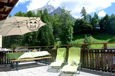 a patio with a table and chairs and an umbrella at San Vito Sunny Terrace IT in San Vito di Cadore