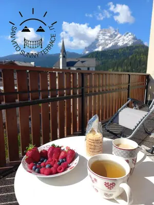 a table with a plate of strawberries and two cups of tea at San Vito Sunny Terrace IT in San Vito di Cadore