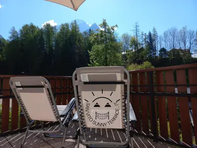 two chairs and a trash can on a patio at San Vito Sunny Terrace IT in San Vito di Cadore