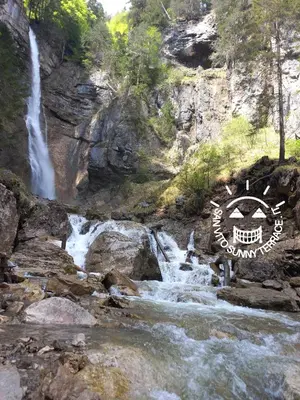 a waterfall in a river with a sign in front of it at San Vito Sunny Terrace IT in San Vito di Cadore