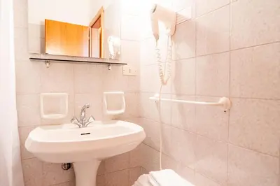 a white bathroom with a sink and a phone at Enrosadira in Predaia