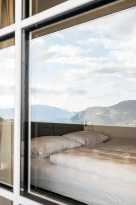 a bedroom with a bed with white sheets and a window at Bella Posta Hotel in Soprabolzano