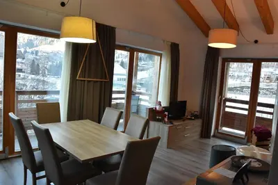 a dining room with a table and chairs and windows at Sass Pordoi Moena in Moena