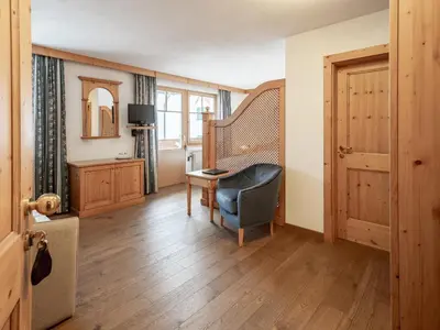 a room with a chair and a desk and a window at Hotel Bad Waldbrunn in Monguelfo