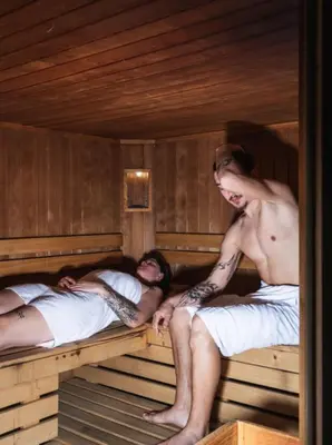two men laying on beds in a sauna at Hotel Bad Waldbrunn in Monguelfo