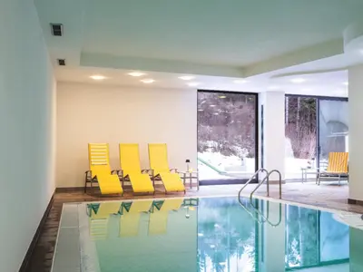 a room with a pool with yellow chairs next to at Hotel Bad Waldbrunn in Monguelfo