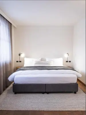 a bedroom with a large bed with white sheets at Hotel Bad Waldbrunn in Monguelfo