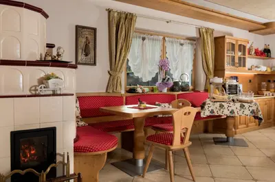 a living room with a table and a fireplace at Garnì Val de Grepa in Pozza di Fassa