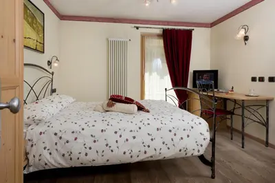 a bedroom with a bed and a table and a desk at Garnì Val de Grepa in Pozza di Fassa