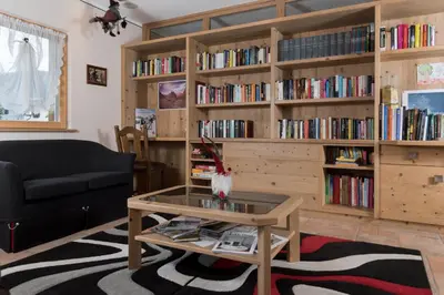 a living room with a coffee table and bookshelves at Garnì Val de Grepa in Pozza di Fassa