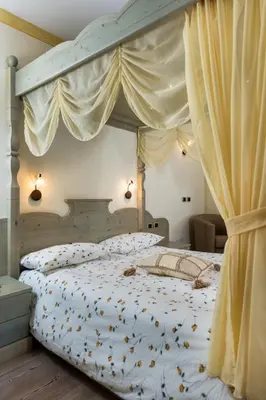 a bedroom with a canopy bed with flowers on it at Garnì Val de Grepa in Pozza di Fassa