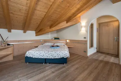 a bedroom with a bed and a wooden ceiling at Garnì Val de Grepa in Pozza di Fassa