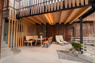 a patio with a table and chairs and wooden walls at zuLAVOGL in Kastelruth